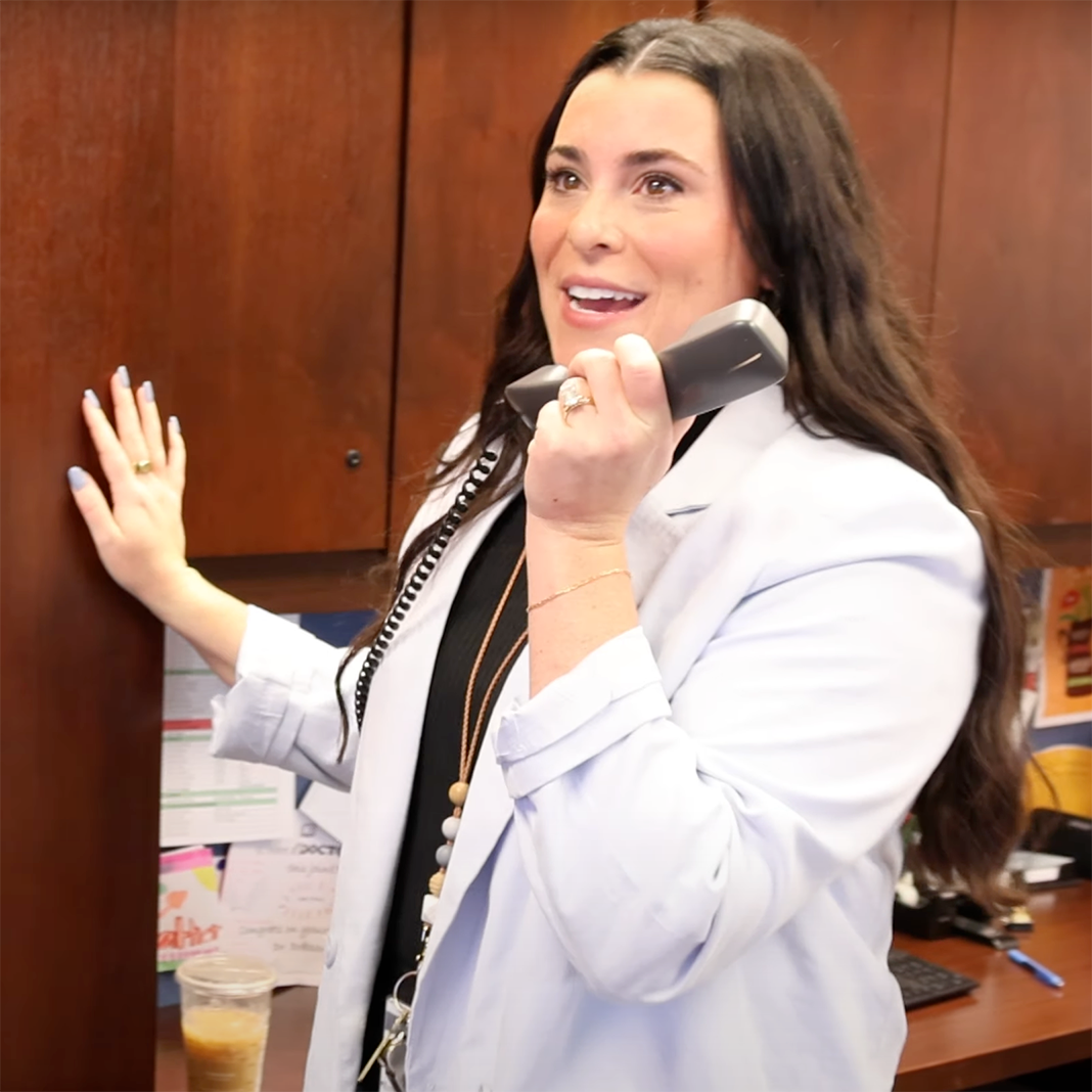  Emma Dennell holds a phone to her mouth to speak over the intercom